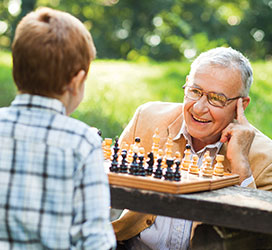 Grandfather and grandson playing chess. Links to Gifts of Life Insurance
